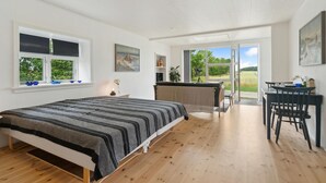 Un dormitorio espacioso con una cama grande, una zona de comedor y vistas al exterior.
