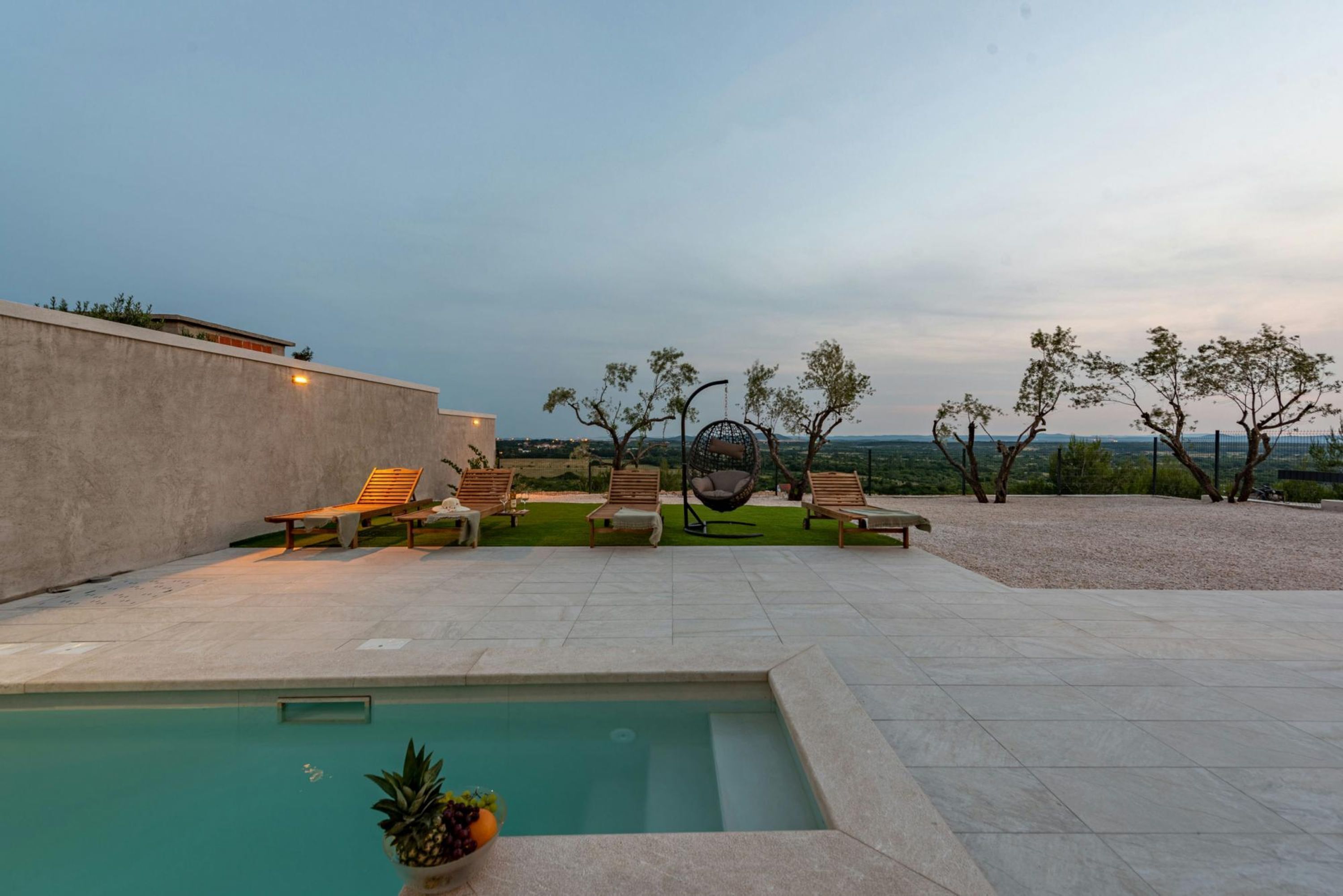 Ein Poolbereich mit Liegestühlen, einer Hängematte und Blick auf die Landschaft.
