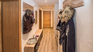 Ein Flur mit Holzboden, einer Bank und Mänteln, die an der Wand hängen.