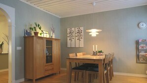 Un coin repas avec une table et des chaises en bois, un buffet et des œuvres d’art murales.