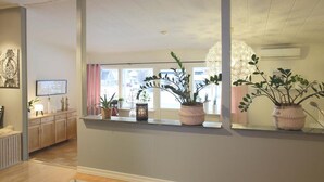 Un intérieur moderne avec un plancher en bois, une fenêtre offrant une belle vue et une étagère ornée de plantes en pot.