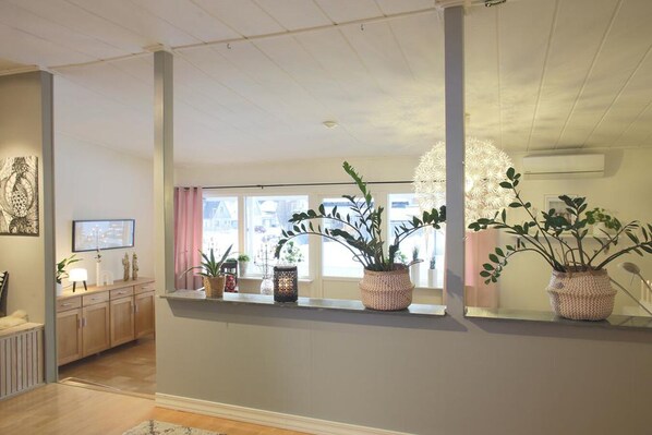 A modern interior with a wooden floor, a window with a view, and a shelf with potted plants. - Aurora Cabin (Kiruna)