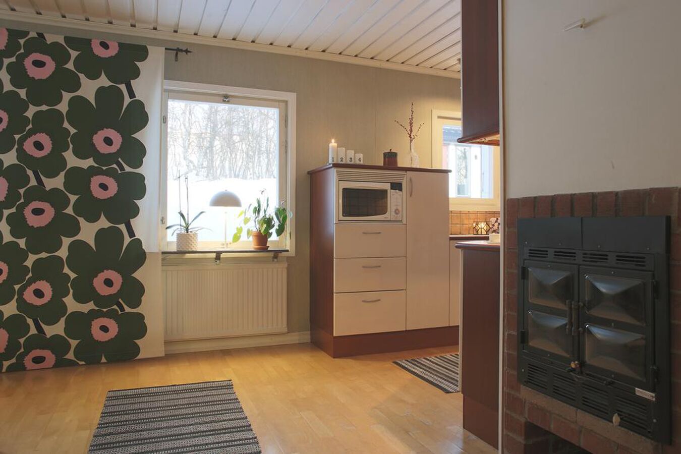 A compact kitchen with a built-in oven, a microwave, and a brick fireplace.