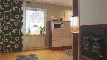 A compact kitchen with a built-in oven, a microwave, and a brick fireplace.