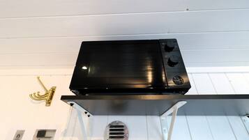 A black electronic device mounted on a white wall with a gold-colored hook and a vent.