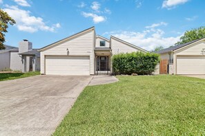 A two-story house with a garage, a front yard, and a small garden area.