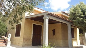 Un bâtiment à deux étages doté d’un patio couvert, de murs en pierre et d’une porte en bois.