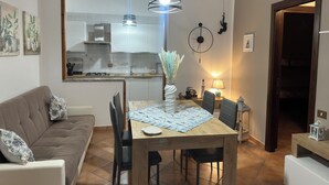 Un salon moderne avec un canapé, une table à manger, des chaises et une cuisine en arrière-plan.