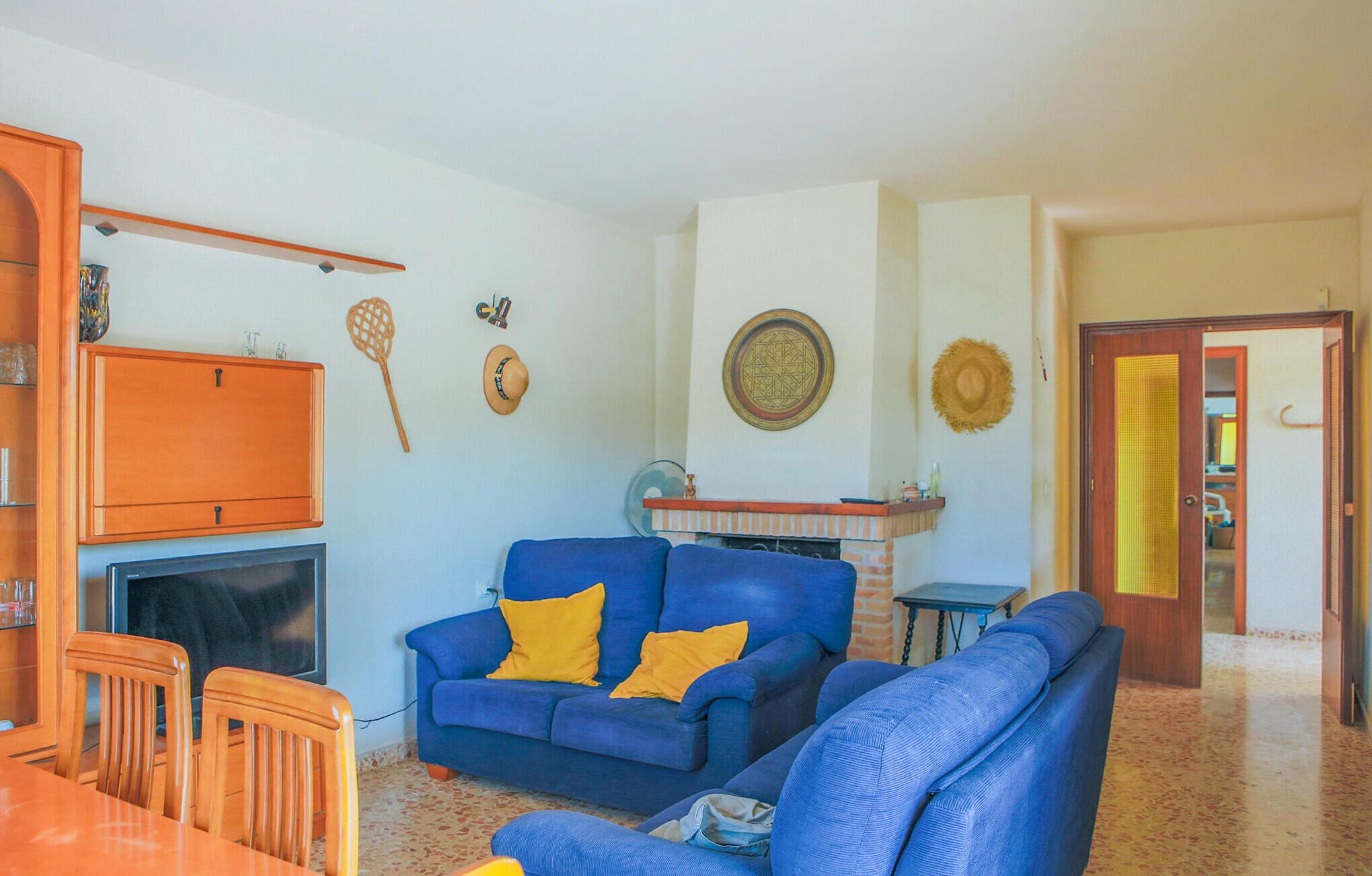 A living room with a blue sofa set, a wooden cabinet, and a fireplace.