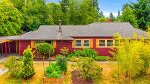 A house with a sloped roof, a chimney, and a front porch. - Boho Bliss Bungalow (Shoreline)