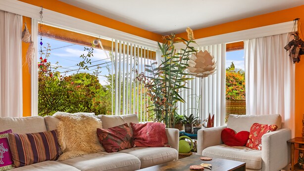 A living room with a sofa, armchairs, a coffee table, and a large window with vertical blinds. - Boho Bliss Bungalow (Shoreline)