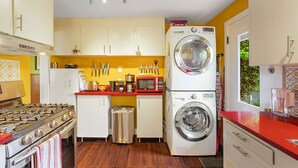A compact kitchen with a gas stove, microwave, and stacked washer-dryer. - Boho Bliss Bungalow (Shoreline)