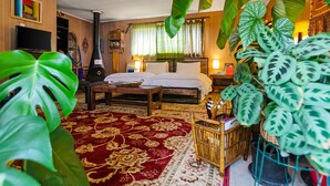 A room with a bed, a television, a heater, and various plants. - Boho Bliss Bungalow (Shoreline)