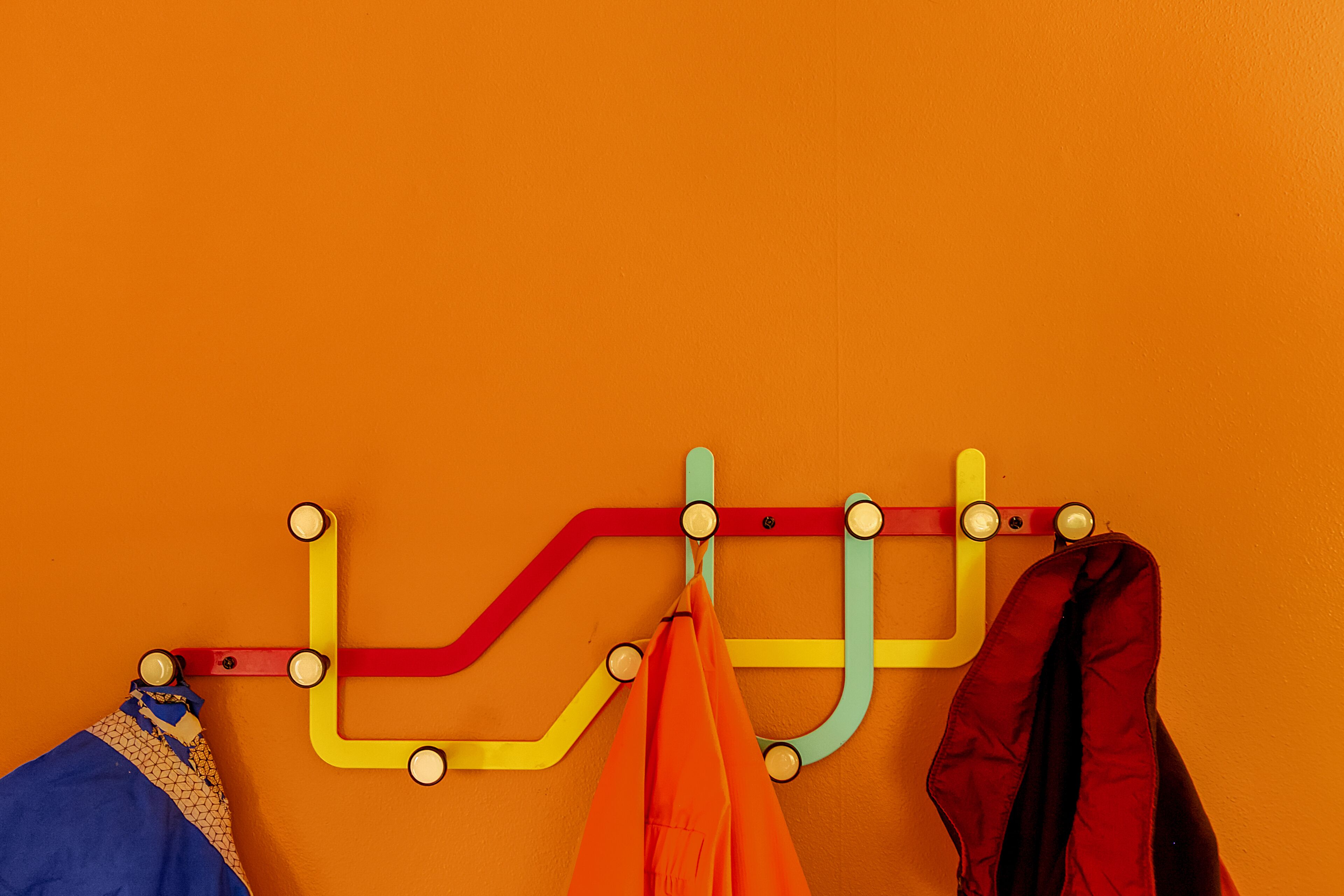 A wall-mounted coat rack with multiple hooks and a hanging bag.