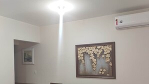 Een woonkamer met een bank, een stoel, een bijzettafeltje en een wandairconditioner.