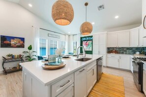 A modern kitchen with white cabinets, a large island, and pendant lighting.
