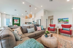 A modern living room with a sofa, armchairs, a coffee table, and a kitchen area in the background.