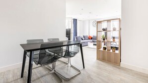 A modern living room with a dining area, a sofa, a coffee table, and a bookshelf. - Stylish Top-Floor Flat (South Harrow)