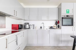 A modern kitchen with white cabinets, a red microwave, a coffee maker, and a toaster.