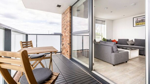 A modern apartment with a balcony, a dining area, and a living room with a sofa and coffee table. - Stylish Top-Floor Flat (South Harrow)