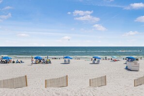 A beach with umbrellas, lounge chairs, and a lifeguard tower.