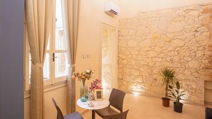 Un comedor con pared de piedra, una araña y una mesa con sillas.