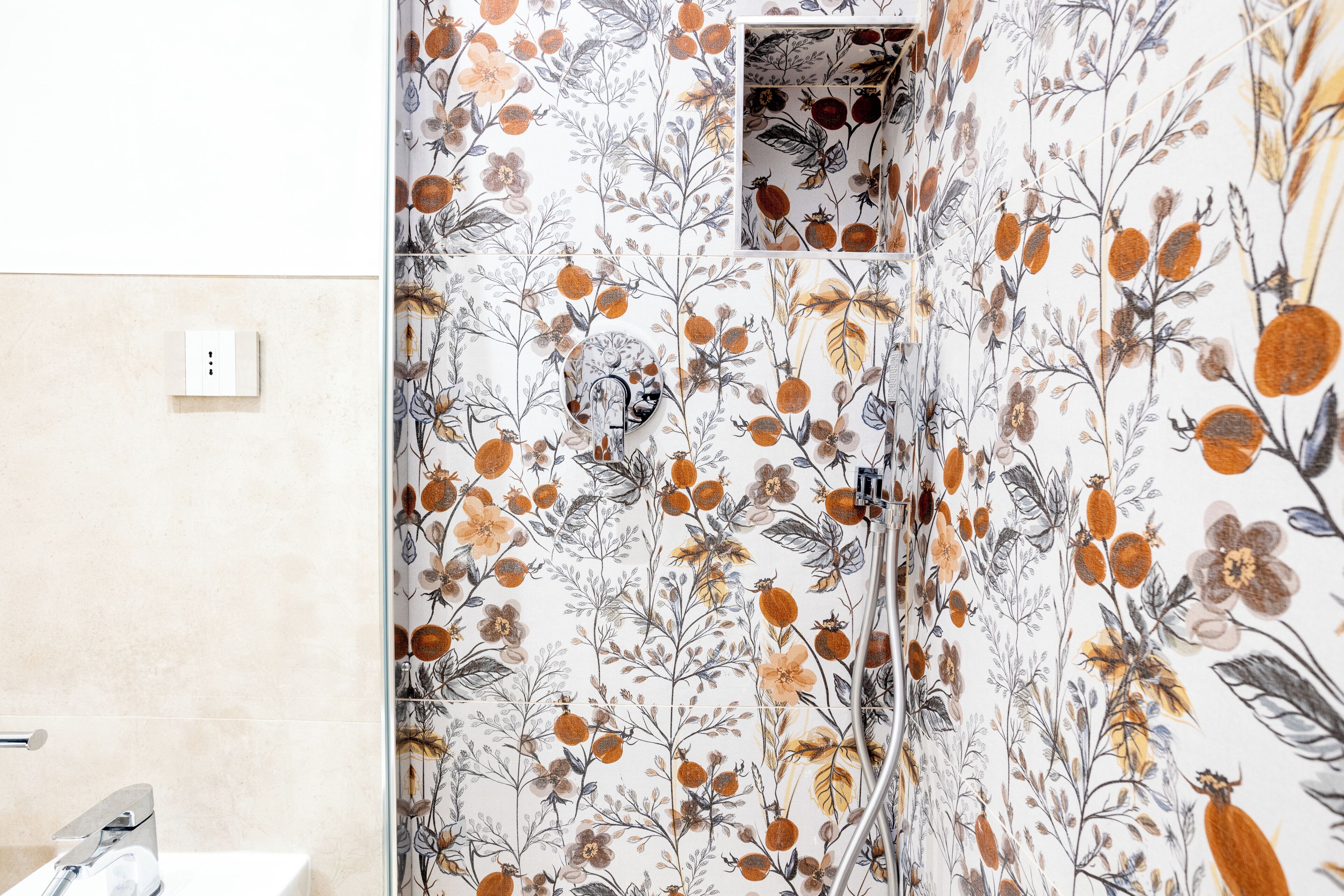 Un baño con estampado de papel tapiz floral, una ducha y un inodoro.