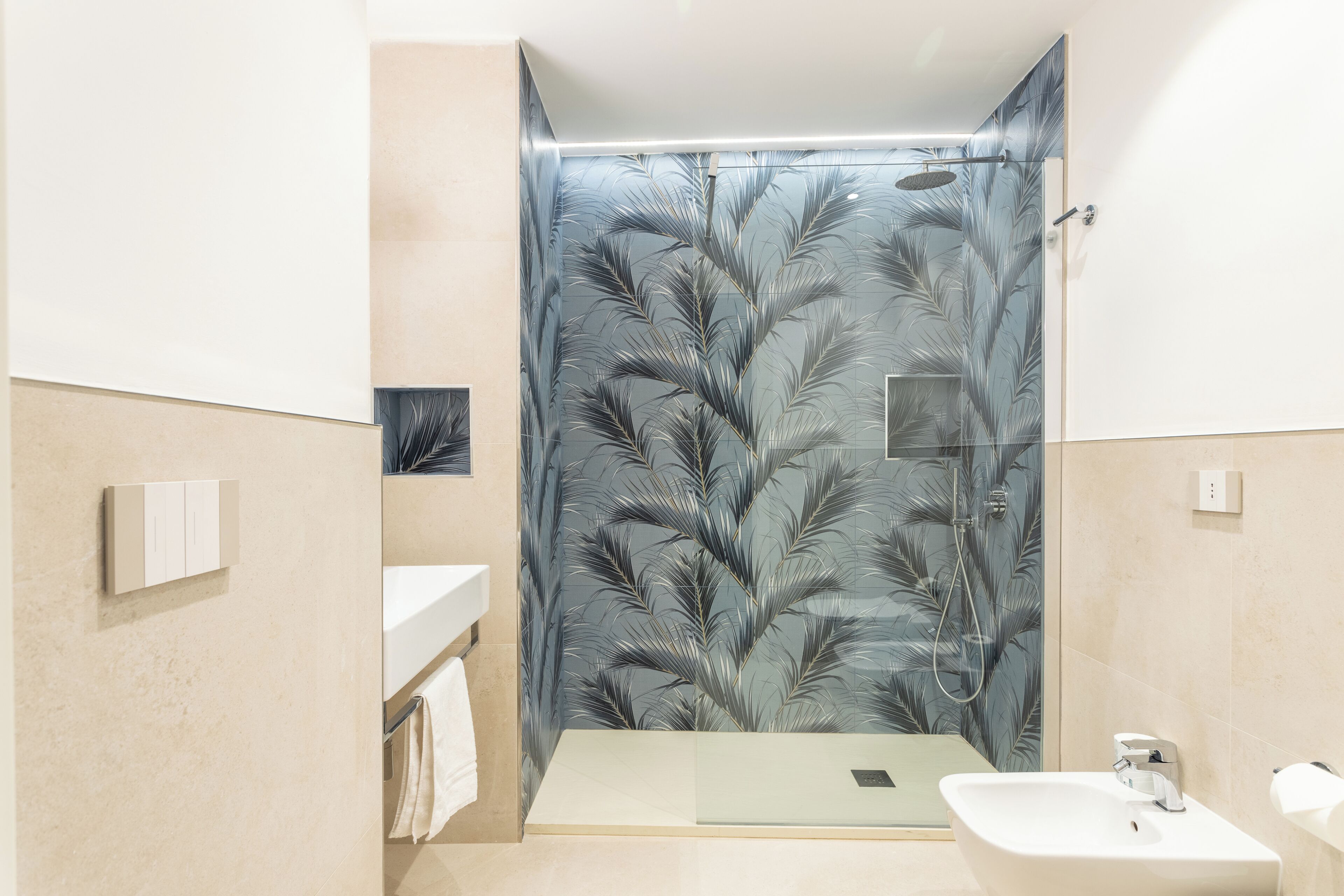 A modern bathroom with a glass shower enclosure, a white sink, and a towel rack.