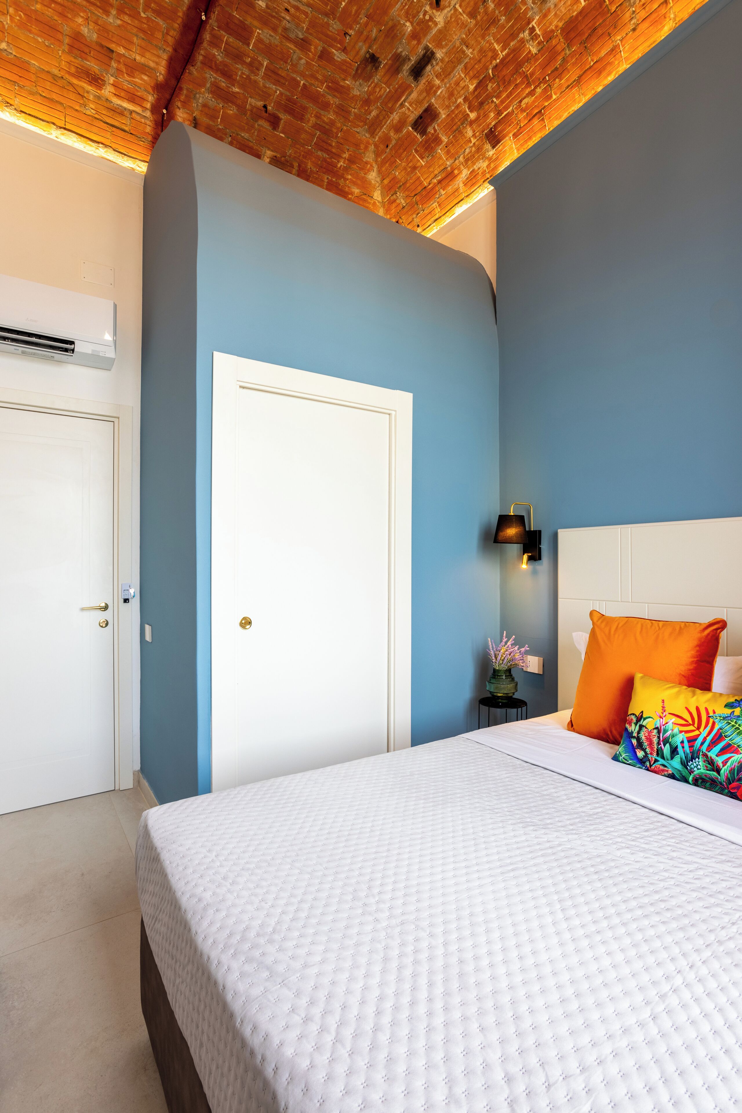 Un dormitorio con una cama blanca, una pared azul y un techo de madera.