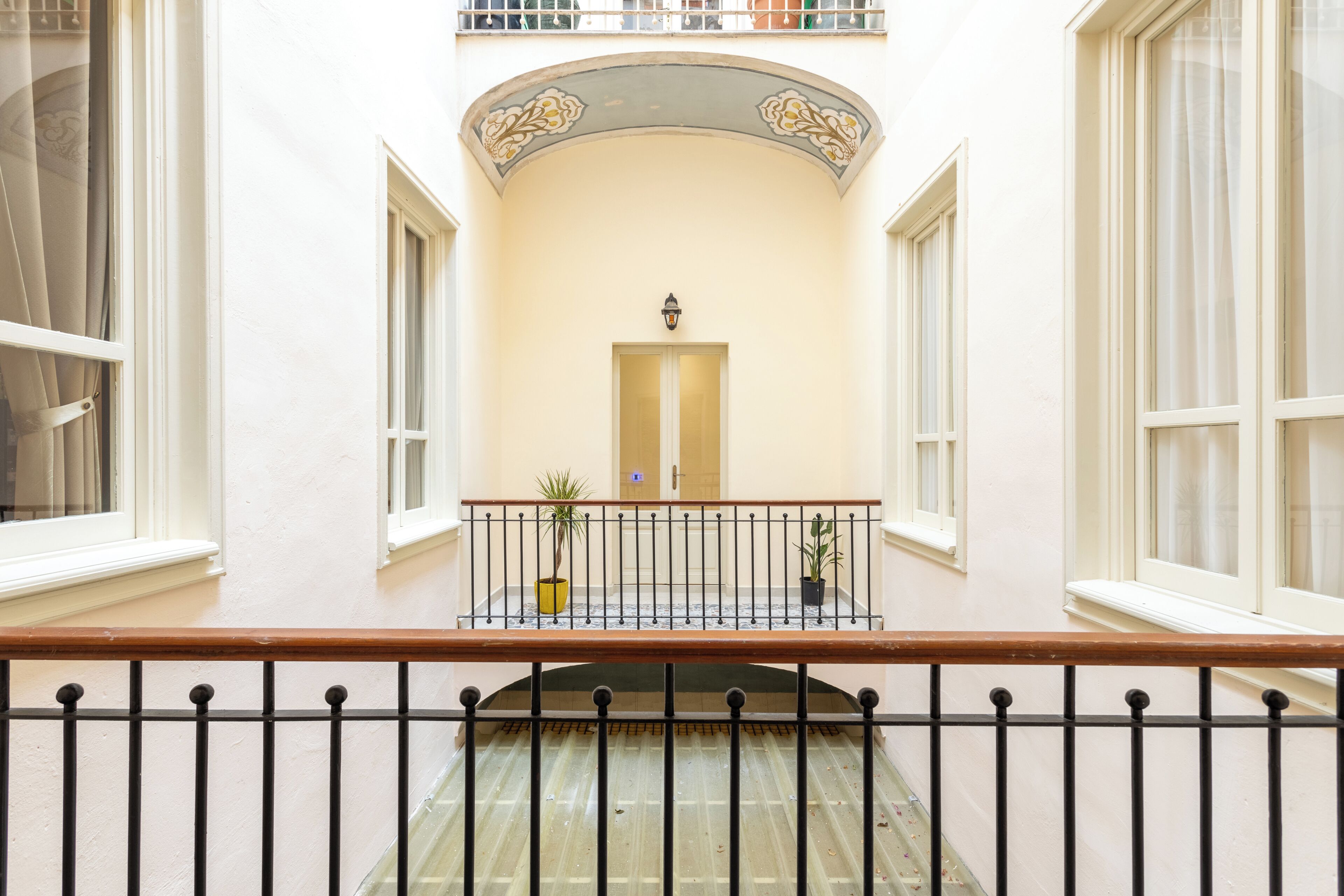 Ein Korridor mit Balkon, Topfpflanze und einer Tür.