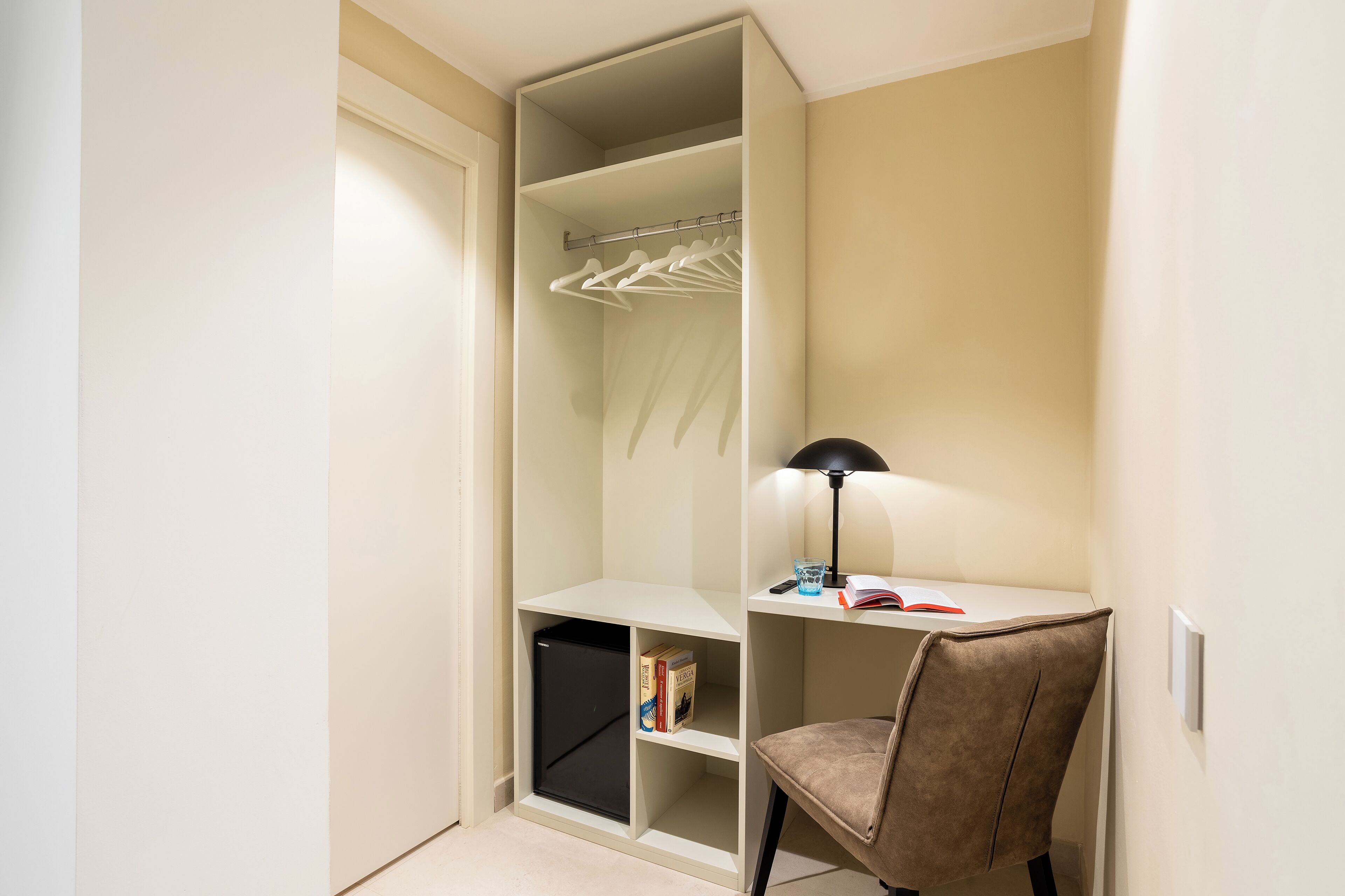 A compact room with a desk, chair, and a built-in wardrobe.