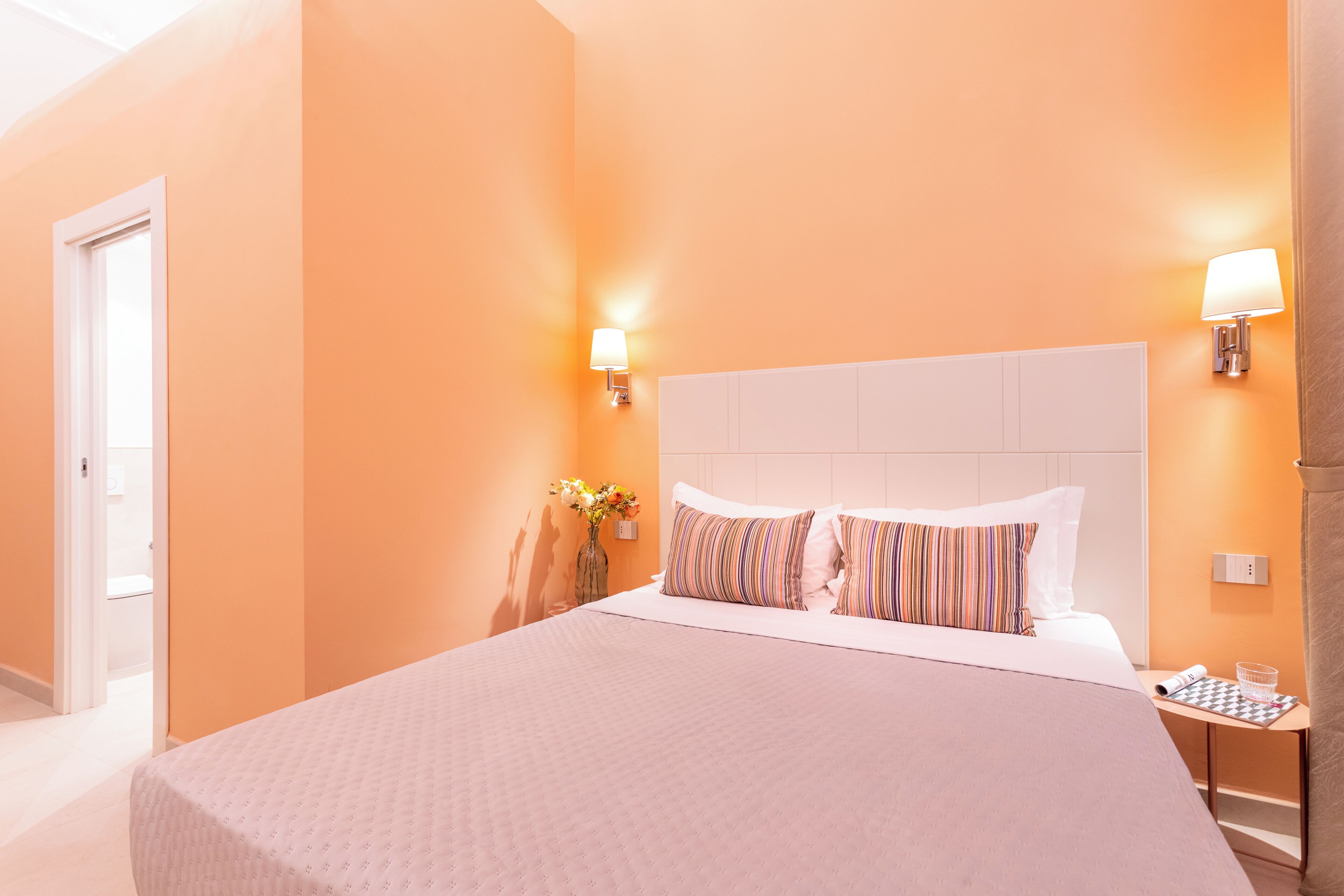 Ein Hotelzimmer mit einem großen Bett, zwei Nachttischlampen, einer Blumenvase und einer karierten Tischdecke.