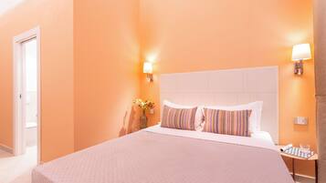 Ein Hotelzimmer mit einem großen Bett, zwei Nachttischlampen, einer Blumenvase und einer karierten Tischdecke.
