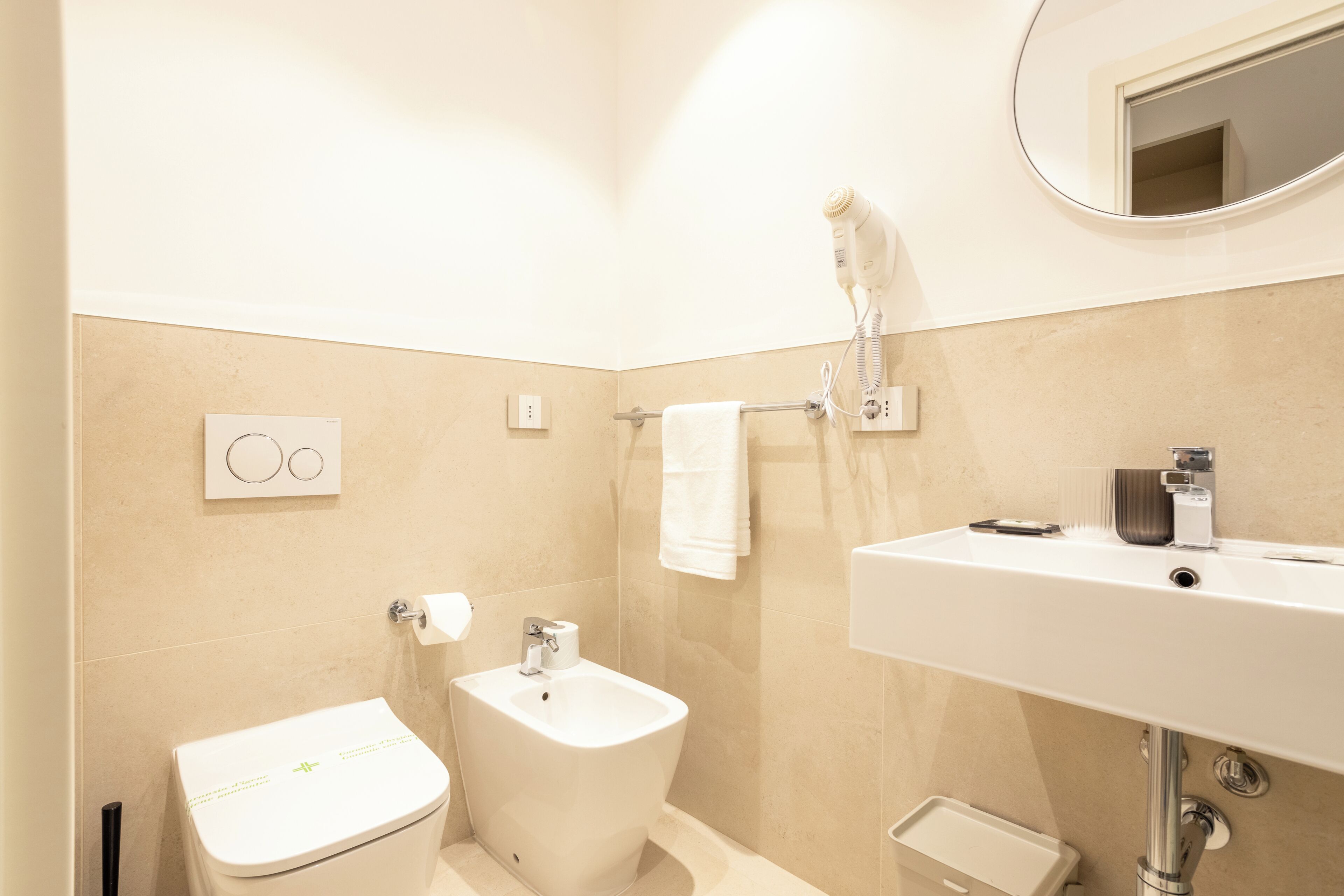 Un baño con inodoro, bidé, lavabo y un perchero para toallas.