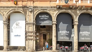 Un edificio histórico con varias fachadas comerciales, incluyendo una cafetería llamada 'Caffè Borbone'.