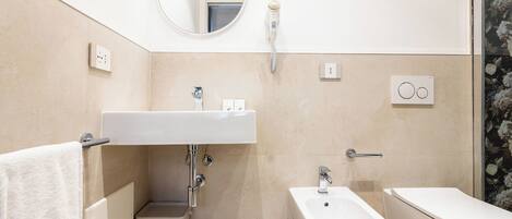 A modern bathroom with a sink, bidet, toilet, and a mirror.