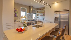 Une cuisine moderne dotée d’un grand îlot central, d’appareils électroménagers en acier inoxydable et d’un design minimaliste.