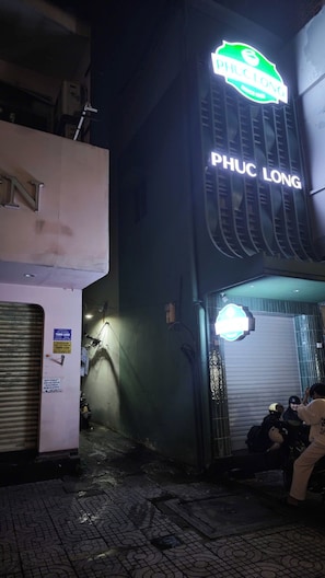 A building with a sign that reads 'PHU LONG' and a closed shutter door. - YOUR HOME - Cozy Studio 25m² 1 (Ho Chi Minh City)