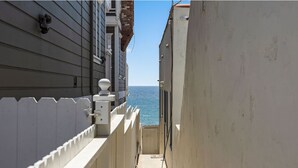 Un couloir étroit donnant sur la mer, une clôture blanche et un bâtiment doté d’un balcon.
