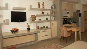 Una cocina moderna con electrodomésticos integrados, un comedor con mesa y sillas, y un televisor de pantalla plana montado en la pared.