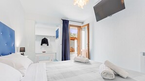 Habitación de hotel moderna con una cama grande, un escritorio, un televisor y vistas al exterior.