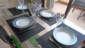 Une table à manger dressée avec des assiettes, des couverts et des verres à vin, et une bouteille de vin posée sur la table.