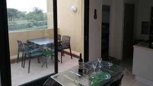 Un balcon avec une table et des chaises, une bouteille de vin et une vue sur la verdure environnante.
