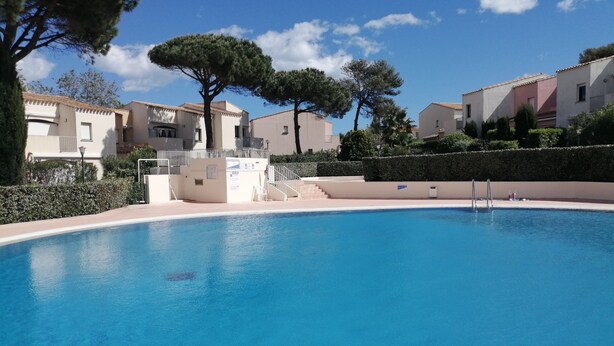 Une piscine à l’eau d’un bleu limpide, entourée d’immeubles et d’arbres.