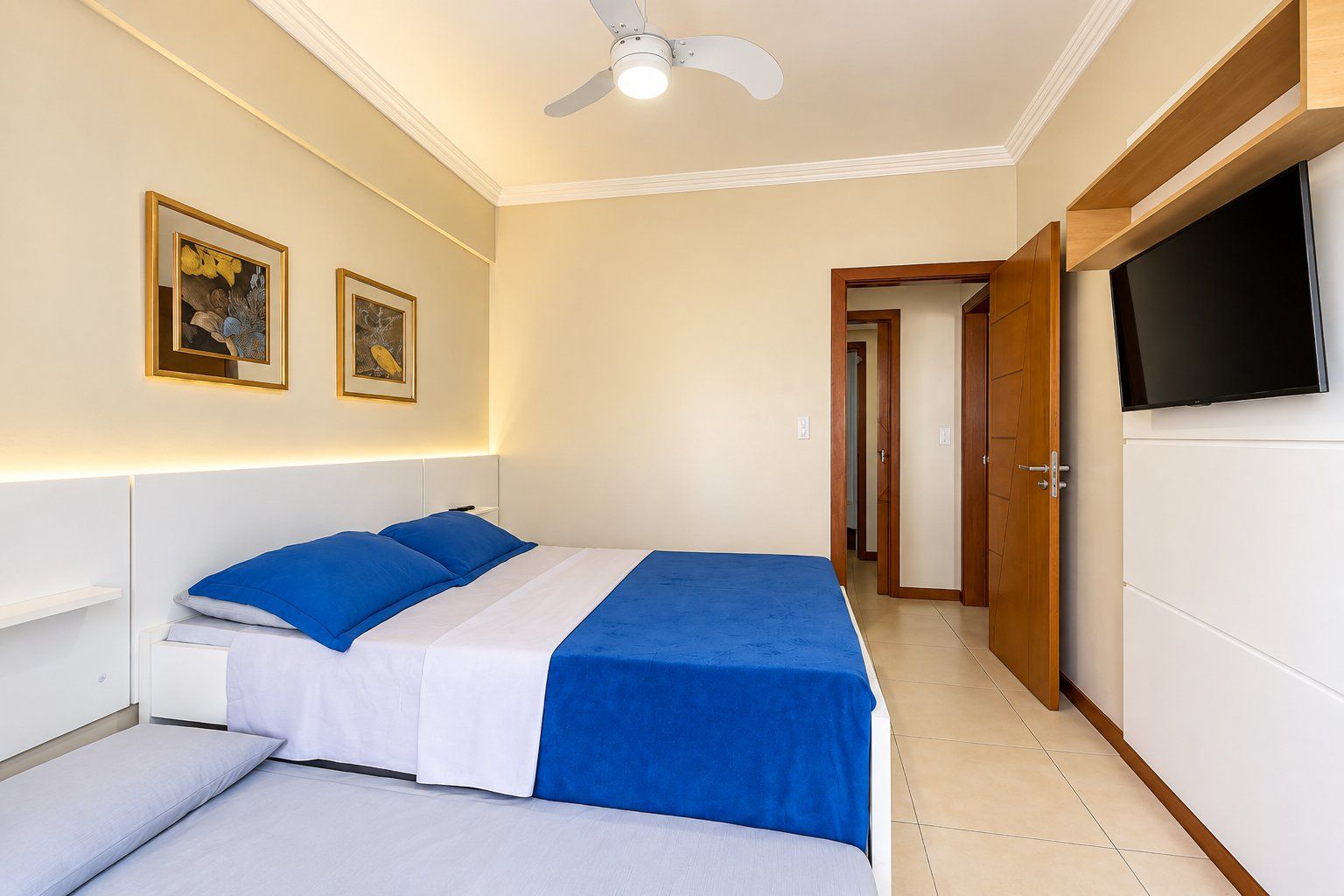 A bedroom with a bed, a TV, and a ceiling fan.