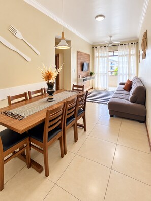 A dining area with a wooden table and chairs, a vase with dried flowers, and a ceiling fan.