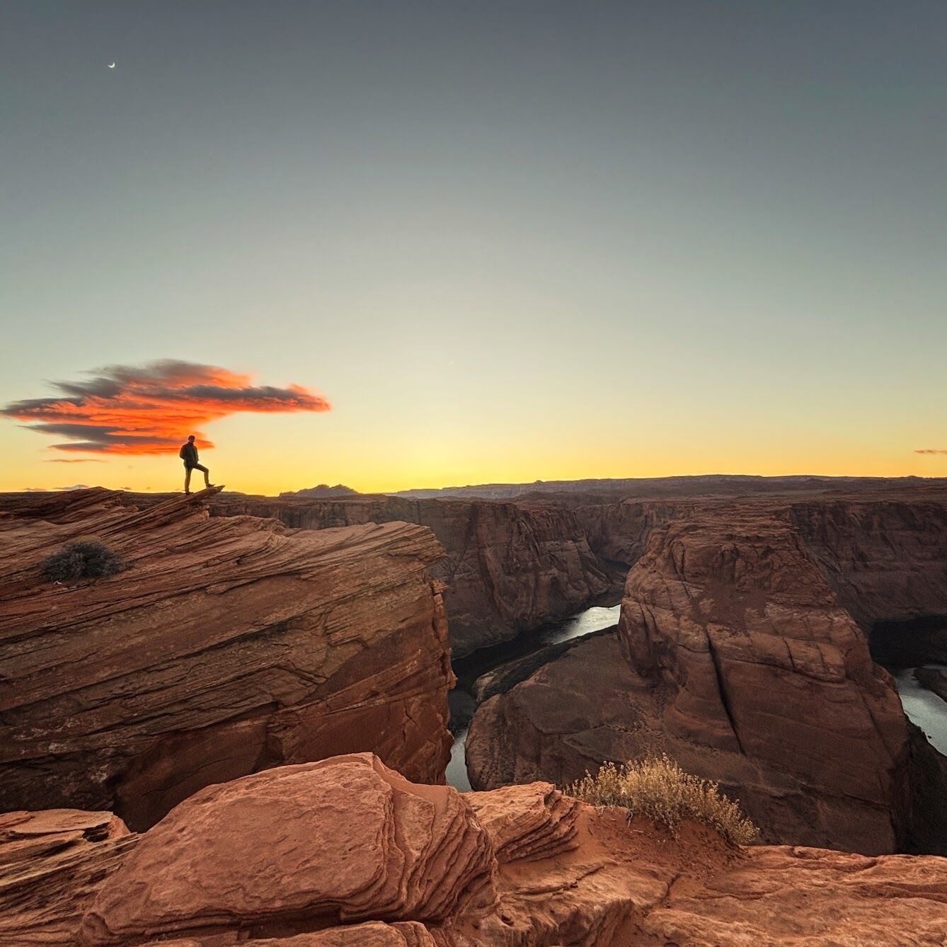 A canyon with a person standing on a rock formation.