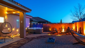 A backyard with a hot tub, outdoor seating, and string lights. - Red Rock Hangout: Big Hot Tub, Firepit, BBQ, Game Room, Communal Spaces (Page)
