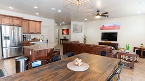 A spacious kitchen with wooden cabinets, a stainless steel refrigerator, and a dining area with a wooden table and chairs. - Red Rock Hangout: Big Hot Tub, Firepit, BBQ, Game Room, Communal Spaces (Page)