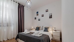 Une chambre à coucher avec un lit, des tables de chevet, une lampe et une fenêtre avec des rideaux.